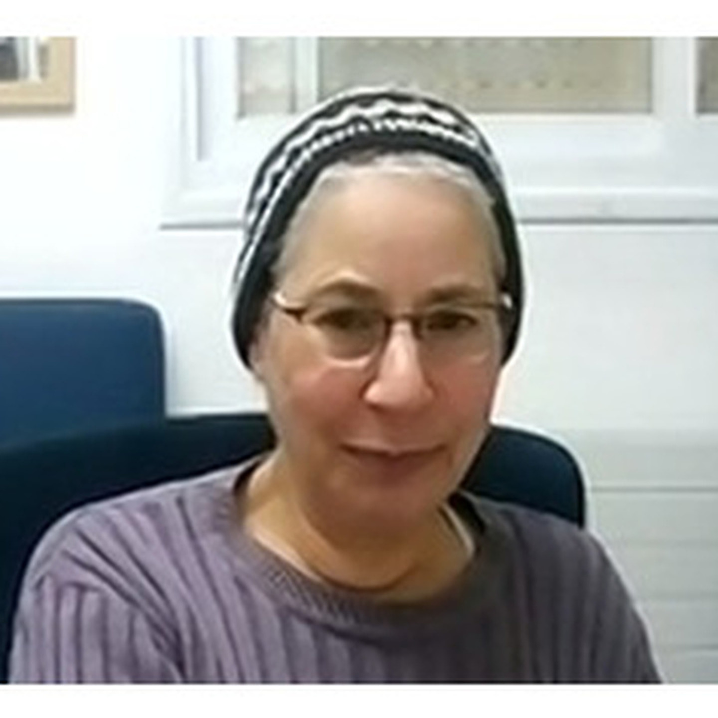 אסתר לנסברג יושבת ומביטה למצלמה