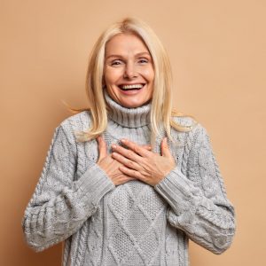 cheerful-good-looking-middle-aged-woman-keeps-hands-pressed-chest-smiles-broadly-expresses-positive-emotions-dressed-winter-jumper-happy-hear-compliment (1)
